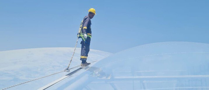 A technician on a crawling board inspecting the upper surface of an inflated ETFE cushion roof