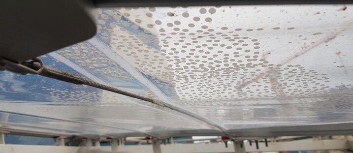 Fritted ETFE panels viewed from below, the printed dots reading as a soft grey texture against the bright sky